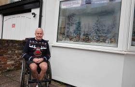 Gentleman sat outside a Christmas scene window