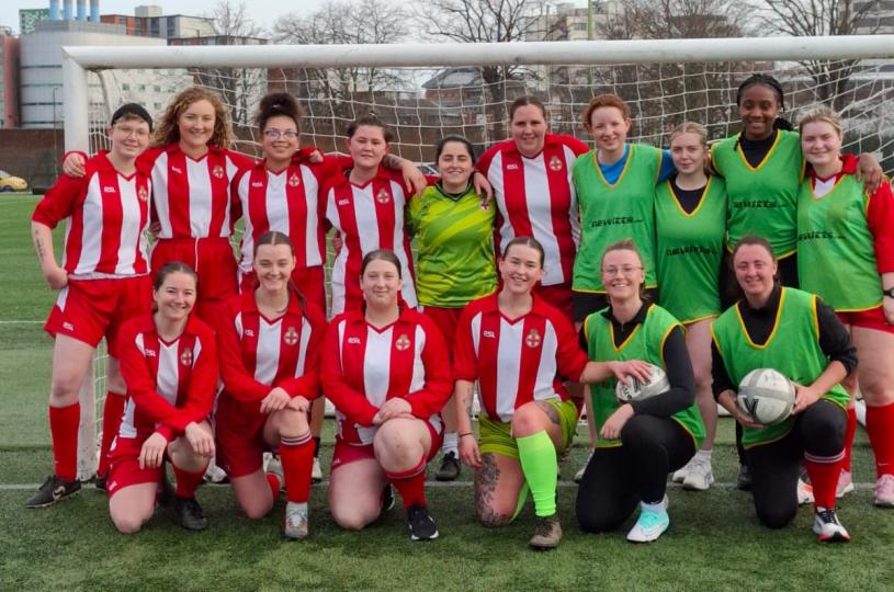 Ladies football team in front of goal posts.