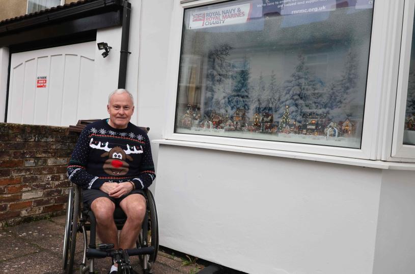 Gentleman sat outside a Christmas scene window