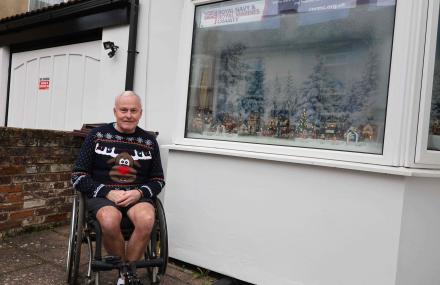 Gentleman sat outside a Christmas scene window